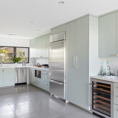 Kitchen - mid-century modern u-shaped gray floor kitchen idea in Orange County with an undermount sink, flat-panel cabinets, green cabinets, white backsplash, stainless steel appliances and white countertops