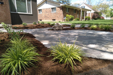 Example of a mid-sized front yard stone patio design in Detroit with no cover