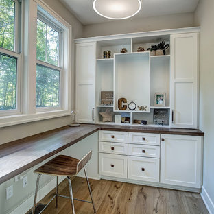 Design ideas for a medium sized modern craft room in Grand Rapids with beige walls, lino flooring, a built-in desk and beige floors.