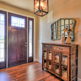 Eklektisk inredning av en mellanstor foajé, med beige väggar, laminatgolv, en enkeldörr, mörk trädörr och brunt golv