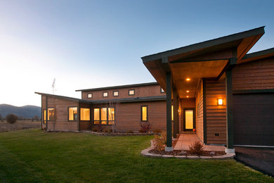 Inspiration for a contemporary two-storey brown house exterior in Other with wood siding.