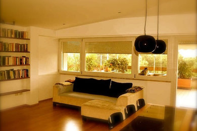 Стильный дизайн: большая открытая гостиная комната в современном стиле с с книжными шкафами и полками, белыми стенами, паркетным полом среднего тона, телевизором на стене и коричневым полом без камина - последний тренд