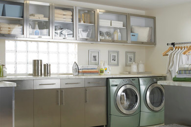 Inspiration for a mid-sized traditional l-shaped utility room in Denver with glass-front cabinets, stainless steel cabinets, granite benchtops, beige walls, ceramic floors and a side-by-side washer and dryer.