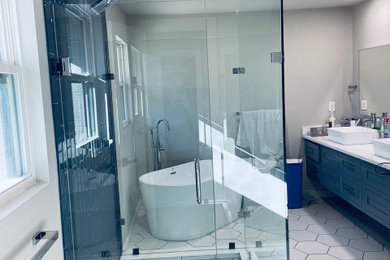 Modelo de cuarto de baño principal y a medida actual de tamaño medio con bañera exenta, ducha abierta, baldosas y/o azulejos azules, baldosas y/o azulejos de vidrio, ducha con puerta con bisagras y encimeras blancas