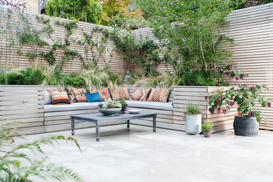 This is an example of a small eclectic patio in London with a container garden and natural stone pavers.