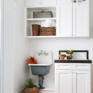Inspiration for an utility room in Houston with a single-bowl sink, shaker cabinets, white cabinets, tile countertops, white walls and terracotta flooring.