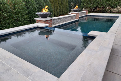 Modelo de piscinas y jacuzzis actuales de tamaño medio rectangulares en patio trasero con adoquines de hormigón