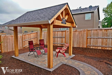 This is an example of a small rustic back patio in Portland with brick paving and an awning.