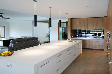 This is an example of a mid-sized modern galley open plan kitchen in Perth with an undermount sink, flat-panel cabinets, medium wood cabinets, quartz benchtops, mirror splashback, stainless steel appliances, ceramic floors, with island and brown floor.