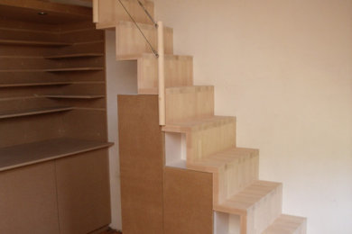 Idée de décoration pour un petit escalier droit design avec des marches en bois, des contremarches en bois, un garde-corps en câble, différents habillages de murs et rangements.
