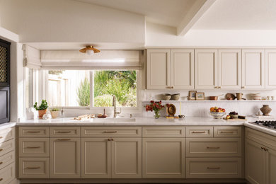 Mid-sized transitional u-shaped medium tone wood floor and brown floor enclosed kitchen photo in Orange County with an undermount sink, shaker cabinets, beige cabinets, marble countertops, white backsplash, marble backsplash, stainless steel appliances, a peninsula and white countertops
