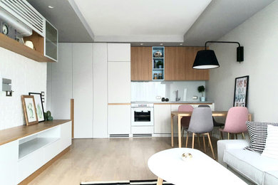 This is an example of a small contemporary grey and pink single-wall open plan kitchen in Other with a built-in sink, flat-panel cabinets, grey cabinets, engineered stone countertops, grey splashback, glass sheet splashback, white appliances, light hardwood flooring, beige floors, grey worktops and a drop ceiling.