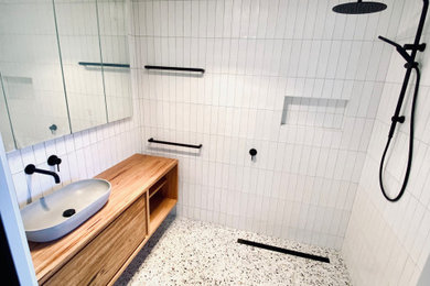 Photo of a small contemporary bathroom in Other with furniture-like cabinets, medium wood cabinets, an open shower, a one-piece toilet, white tile, ceramic tile, white walls, terrazzo floors, a vessel sink, wood benchtops, an open shower, brown benchtops, a single vanity and a floating vanity.