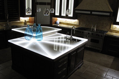 Inspiration for a large modern travertine floor and brown floor kitchen remodel in San Diego with an undermount sink, glass-front cabinets, dark wood cabinets, glass countertops, beige backsplash, ceramic backsplash, stainless steel appliances and an island