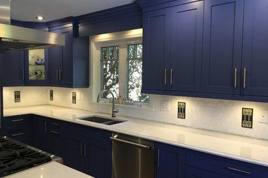 Inspiration for a mid-sized modern open concept kitchen remodel in Vancouver with a double-bowl sink, blue cabinets, quartzite countertops, white backsplash, stone tile backsplash, stainless steel appliances and an island