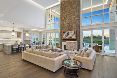 Mediterranean open concept living room in Melbourne with white walls, light hardwood floors, a standard fireplace, a stone fireplace surround and brown floor.