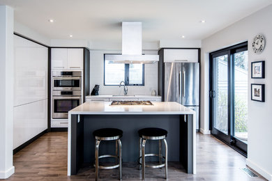 Small minimalist galley medium tone wood floor kitchen photo in Toronto with an undermount sink, flat-panel cabinets, white cabinets, solid surface countertops, white backsplash, ceramic backsplash and stainless steel appliances