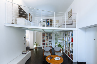 Diseño de biblioteca en casa moderna de tamaño medio con paredes blancas, suelo de pizarra y suelo negro