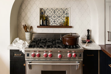 Eat-in kitchen - mid-sized mediterranean u-shaped medium tone wood floor and brown floor eat-in kitchen idea in San Francisco with recessed-panel cabinets, black cabinets, marble countertops, a peninsula, a farmhouse sink, white backsplash, porcelain backsplash, stainless steel appliances and white countertops