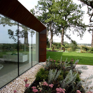 Design ideas for a large contemporary walk-out basement in London with beige walls, limestone flooring, a corner fireplace, a plastered fireplace surround and beige floors.