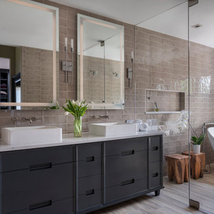 Inspiration for a mid-sized transitional master beige tile and porcelain tile porcelain tile and beige floor bathroom remodel in Denver with furniture-like cabinets, gray cabinets, a one-piece toilet, a vessel sink, quartz countertops, a hinged shower door and white countertops