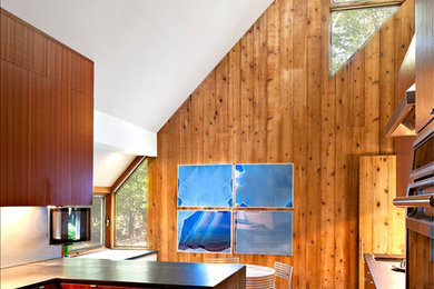 Inspiration for a large modern l-shaped dark wood floor eat-in kitchen remodel in New York with flat-panel cabinets, medium tone wood cabinets, soapstone countertops, metallic backsplash, metal backsplash, stainless steel appliances and a peninsula