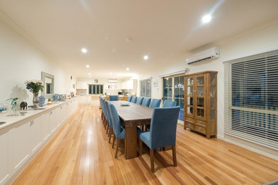 This is an example of a large country open plan dining in Other with beige walls and light hardwood floors.