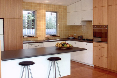 Inspiration for a mid-sized modern l-shaped open plan kitchen in Perth with a double-bowl sink, light wood cabinets, laminate benchtops, yellow splashback, ceramic splashback, stainless steel appliances, light hardwood floors and with island.