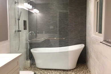 Mid-sized transitional 3/4 black and white tile, gray tile and ceramic tile pebble tile floor and brown floor bathroom photo in Toronto with shaker cabinets, white cabinets and gray walls