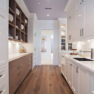 Design ideas for an expansive transitional kitchen pantry in Miami with an undermount sink, shaker cabinets, white cabinets, marble benchtops, white splashback, stone slab splashback, white appliances, medium hardwood floors and with island.