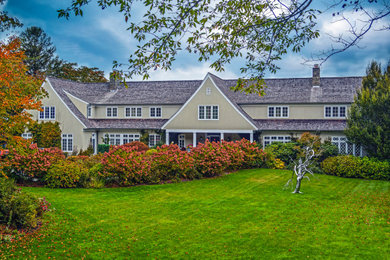 Large elegant two-story stucco house exterior photo in New York with a hip roof and a shingle roof