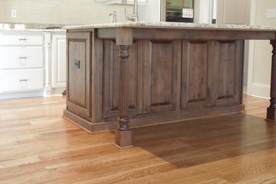 Mid-sized elegant l-shaped medium tone wood floor kitchen pantry photo in Other with an undermount sink, raised-panel cabinets, white cabinets, granite countertops, beige backsplash, stone tile backsplash, stainless steel appliances and an island