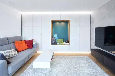 This is an example of a large contemporary enclosed family room in Stuttgart with white walls, no fireplace, a wall-mounted tv, brown floor, a library and light hardwood floors.