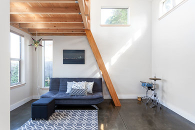 This is an example of a small contemporary loft-style family room in San Francisco with a music area, white walls, concrete floors, no fireplace and no tv.