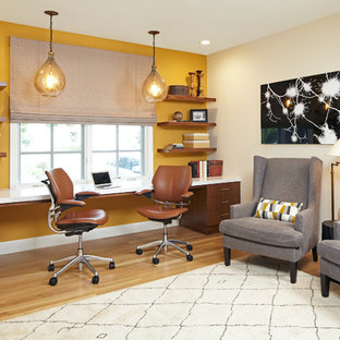 Idéer för att renovera ett stort vintage hemmabibliotek, med gula väggar, ett inbyggt skrivbord och ljust trägolv