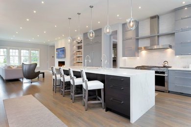 Photo of a large modern u-shaped open plan kitchen in New York with an undermount sink, flat-panel cabinets, grey cabinets, marble benchtops, white splashback, stone slab splashback, stainless steel appliances, light hardwood floors, with island and beige floor.