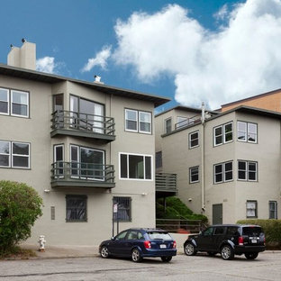 На фото: трехэтажный фасад многоквартирного дома среднего размера серого цвета в современном стиле с облицовкой из цементной штукатурки и плоской крышей с