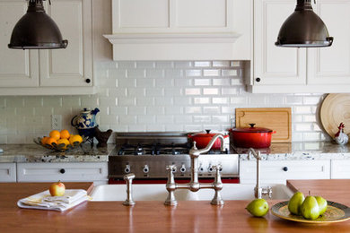 Example of a classic kitchen design in Toronto with wood countertops, a double-bowl sink, raised-panel cabinets, white cabinets, white backsplash and subway tile backsplash
