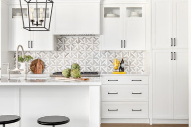 Mid-sized transitional single-wall medium tone wood floor open concept kitchen photo in Vancouver with a farmhouse sink, recessed-panel cabinets, white cabinets, quartz countertops, beige backsplash, mosaic tile backsplash, paneled appliances, an island and white countertops