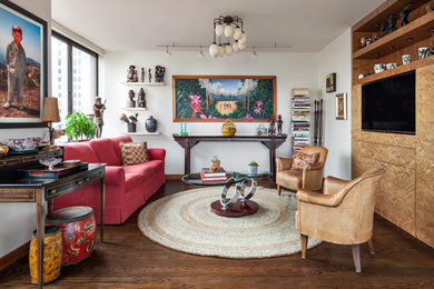 Inspiration for an eclectic family room in New York with white walls, medium hardwood floors, a built-in media wall and brown floor.