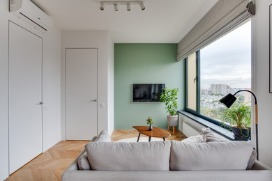 На фото: гостиная комната среднего размера, в белых тонах с отделкой деревом в современном стиле с зелеными стенами и телевизором на стене