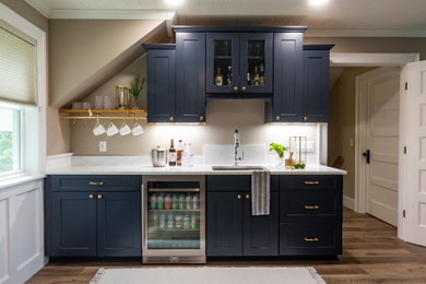 Small ornate single-wall vinyl floor and brown floor wet bar photo in Burlington with an undermount sink, shaker cabinets, blue cabinets, wood countertops, white countertops, white backsplash and quartz backsplash