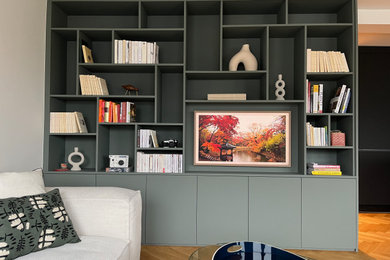 Réalisation d'une salle de séjour minimaliste de taille moyenne avec une bibliothèque ou un coin lecture, un mur vert et un téléviseur fixé au mur.
