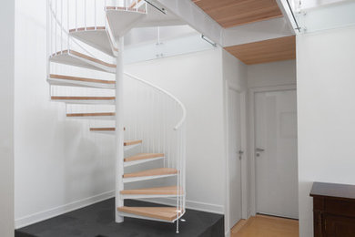 This is an example of a small contemporary wood spiral staircase in Montreal with metal risers and metal railing.