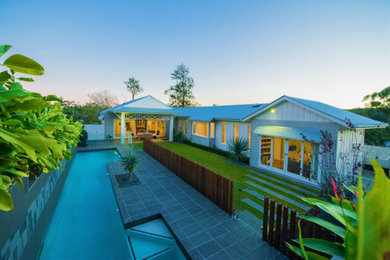 Photo of a medium sized contemporary back custom shaped lengths swimming pool in Brisbane with natural stone paving.