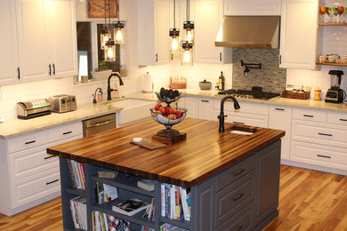 Inspiration for a large country single-wall open plan kitchen in San Francisco with a farmhouse sink, flat-panel cabinets, white cabinets, wood benchtops, white splashback, porcelain splashback, stainless steel appliances, medium hardwood floors, with island, multi-coloured floor and brown benchtop.