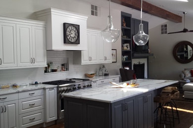 Example of a mid-sized mountain style u-shaped dark wood floor open concept kitchen design in Denver with raised-panel cabinets, white cabinets, marble countertops, white backsplash, subway tile backsplash, stainless steel appliances, an island and an integrated sink
