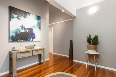 Photo of a large transitional foyer in Brisbane with grey walls, medium hardwood floors, a single front door, a medium wood front door and brown floor.