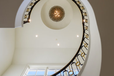 Example of a large classic wooden curved metal railing staircase design in Dallas with marble risers