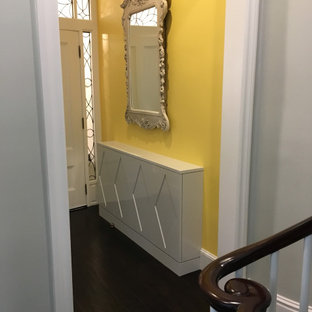Photo of a small eclectic foyer in Boston with yellow walls, dark hardwood floors, a single front door and brown floor.